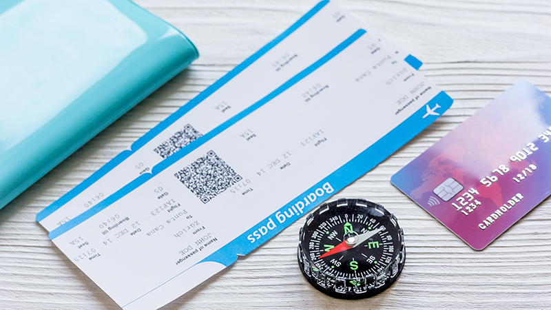 A picture of a passport holder, boarding passes, compass and credit card